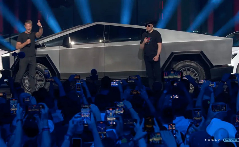 Elon Musk standing next to a Cybertruck.