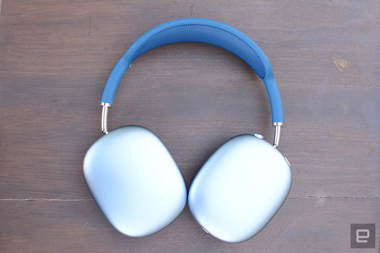 The blue Apple AirPods Max headphones lay flat on a brown wooden tabletop.