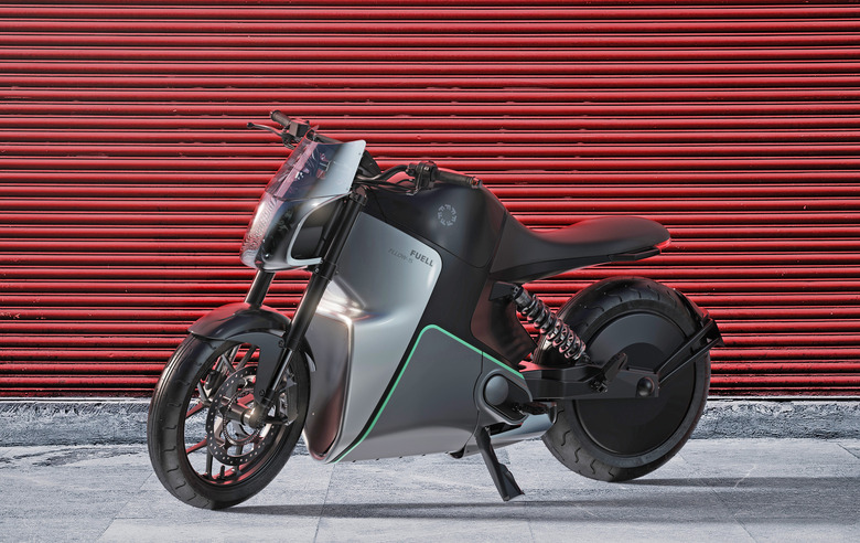 A press photo of Fuell Flloww electric motorcycle seen from the side on a sidewalk in front of a red roll down metal gate.