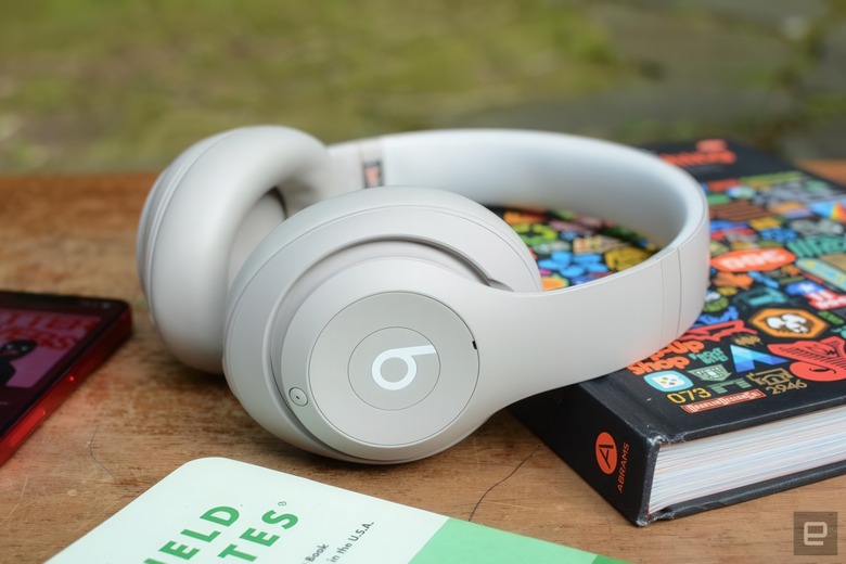 The Beats Studio Pro headphones leaning against a book. Other books are nearby.