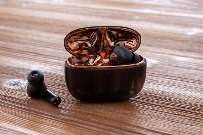 Creative's Aurvana Ace wireless headphones pictured on a table with the charging case open.