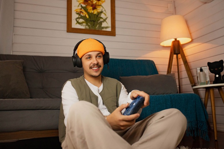 A person wearing an Xbox Wireless Headset over their beanie and holding a controller.