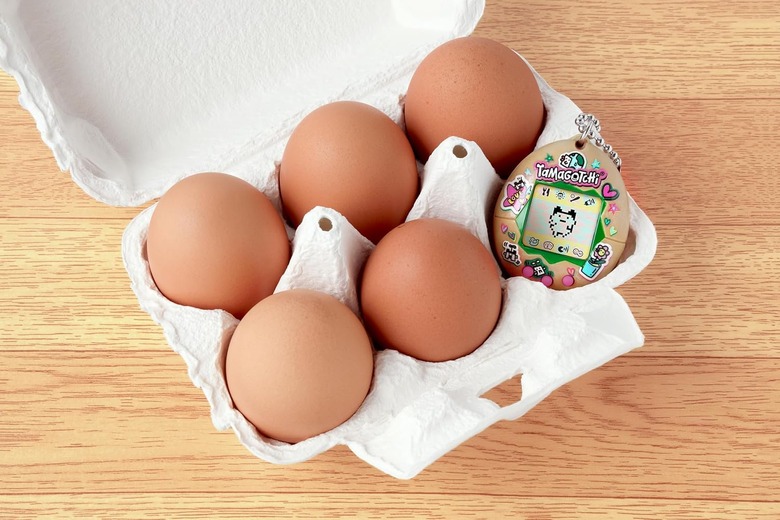 A carton of eggs with a Tamagotchi.