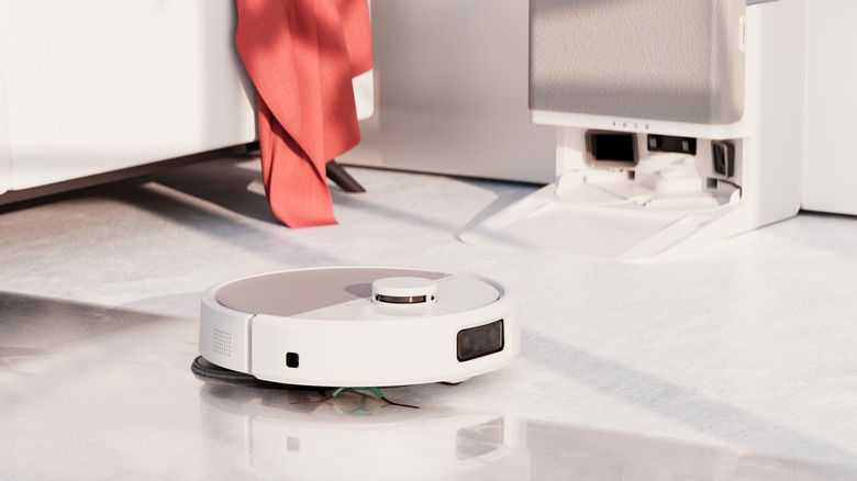 A white Roomba cleaning a floor.