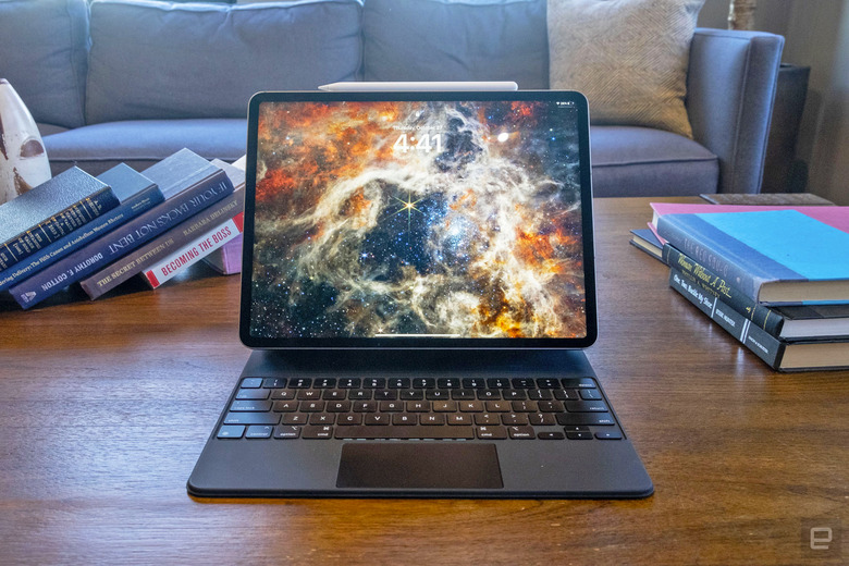 An Apple iPad Pro M2 (2022) sits on a coffee table, facing the camera with its keyboard connected. The screen saver is one of the space images from the James Webb Space Telescope.