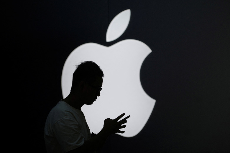 A man check his phone near an Apple logo outside its store in Shanghai, China September 13, 2023. REUTERS/Aly Song