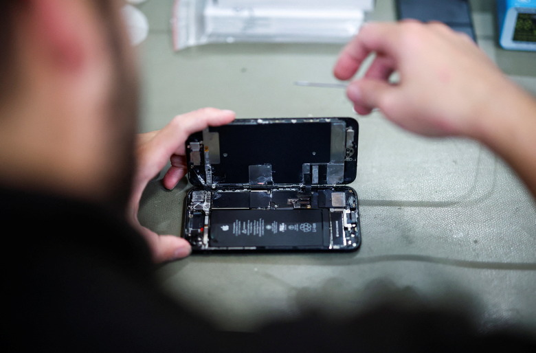 A smartphone repair technician works on a Apple iPhone SE in Saint-Sebastien-sur-Loire, near Nantes, October 7, 2024. REUTERS/Stephane Mahe