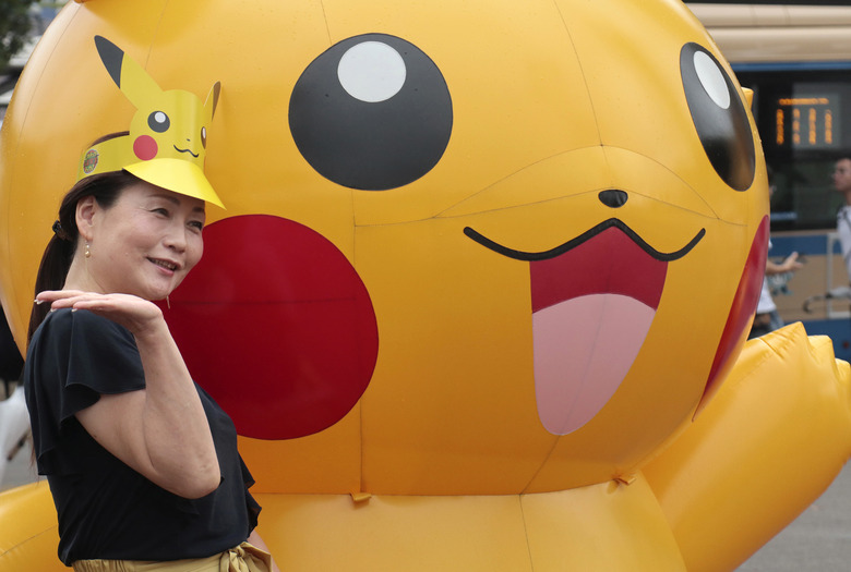A woman poses with a balloon of Pokemon character Pikachu at Minatomirai shopping district in Yokohama, near Tokyo, Monday, Aug. 14, 2017. (AP Photo/Shizuo Kambayashi)