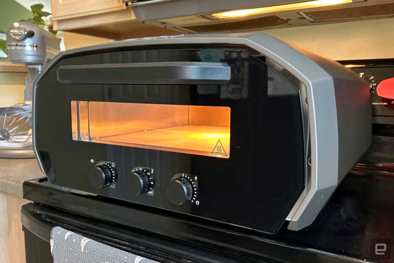 A pizza oven on top of a regular oven.