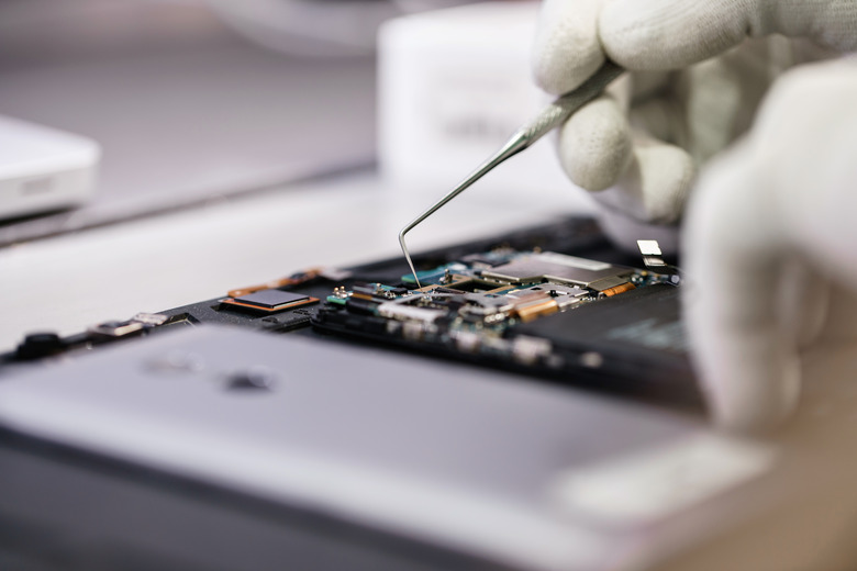 Work with a microscope. Microelectronics device. Close-up hands of a service worker repairing modern smartphone.