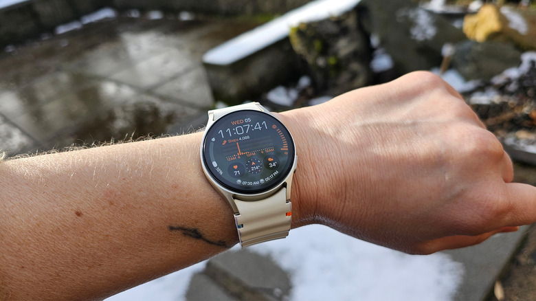 The Samsung Galaxy Watch 7 on a person's wrist outside. There's some snow in the background. 