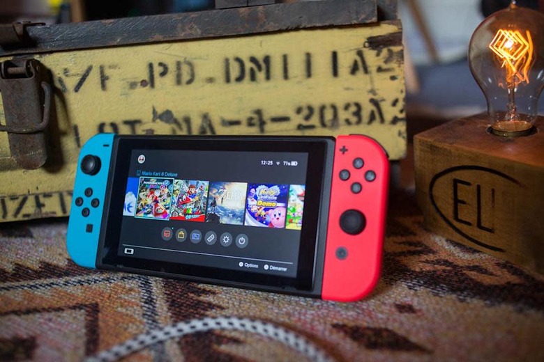 A photo of the original Nintendo Switch with detachable red and blue controllers, behind an antique crate and lamp