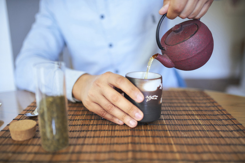 Front view close-up of man pouring tea in a cup