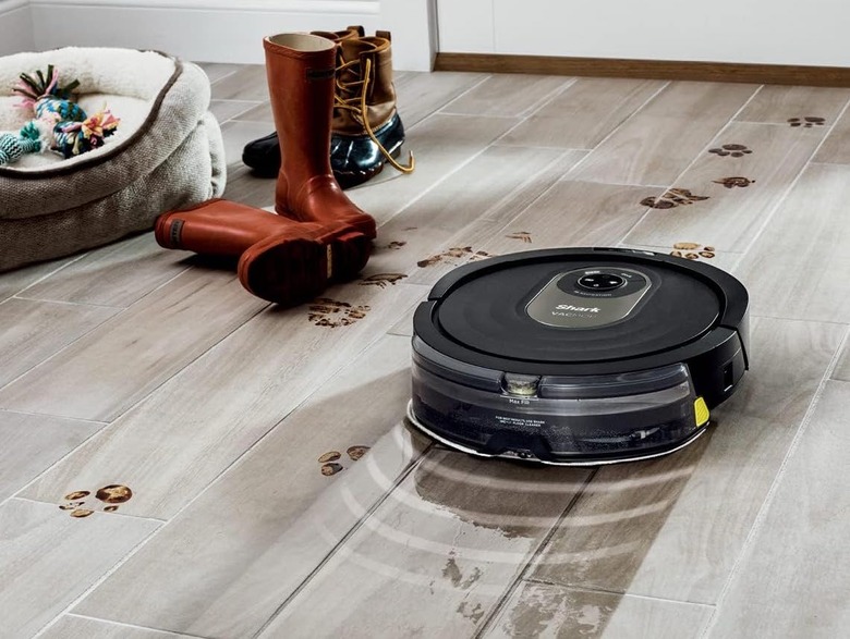 The Shark vacuum cleans a dirty wood floor. 