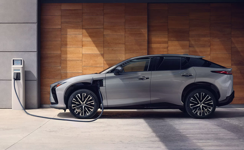 A photo render of a Lexus RZ electric vehicle plugged into a charging outlet. 