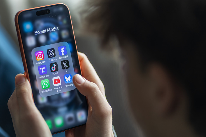 BATH, UNITED KINGDOM - MARCH 29: In this photo illustration a 14-year-old boy holds an iPhone screen displaying various social media and messaging apps on March 29, 2026 in Bath, England. On top row left to right, the logo of social media platform Instagram is seen beside that of Meta’s Threads and Facebook. On the middle row from left is the logo of Donald Trump's Truth Social app, next to the logo of social media app TikTok and the logo of Elon Musk’s US online social media and social networking site 'X' (formerly known as Twitter). Along the bottom row, left to right is the messaging service WhatsApp, the logo for online video sharing and social media platform YouTube and the logo for the Bluesky app. In the UK, a ban on social media for under-16s has been backed by the House of Lords following the Australian law which aims to stop children under 16 from having social media accounts and social media platforms, including TikTok, Facebook, Snapchat, Reddit, X, formerly Twitter, and Instagram potentially being be fined for preventing children younger than 16 from having social media accounts. (Photo by Anna Barclay/Getty Images)