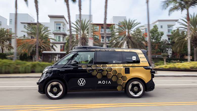 An autonomous VW ID. Buzz microvan on a palm tree-lined street