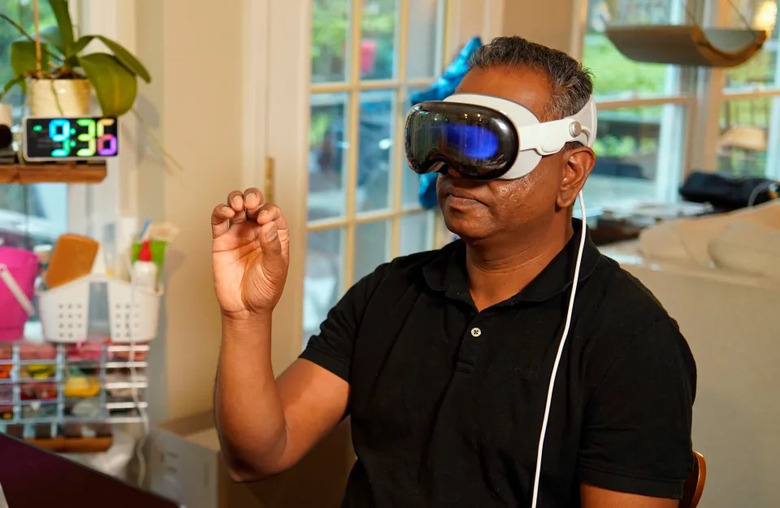Engadget editor Devindra Hardawar wears the Apple Vision Pro headset and makes a pinching gesture with his hand 