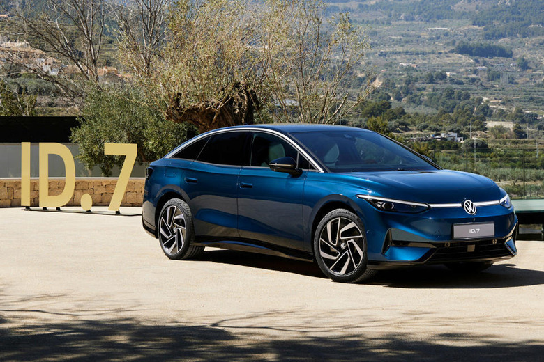 The Volkswagen ID.7 sedan (blue) sitting on a driveway with a sign reading 