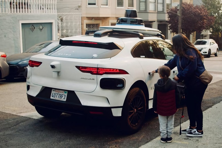 A woman and child stepping into an autonomous Waymo car