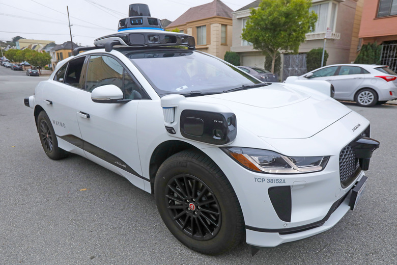 A white Waymo self-driving SUV is parked in the street.