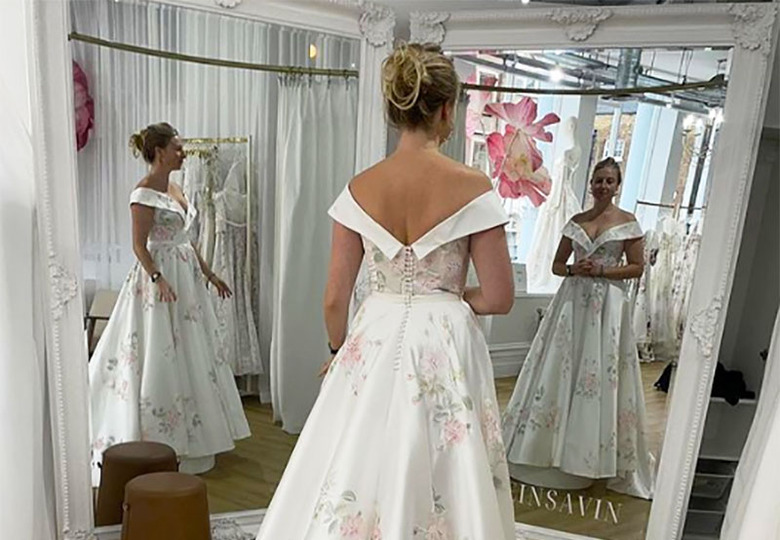 A woman in front of a dual mirror represented as three women, each with different arm positions.   