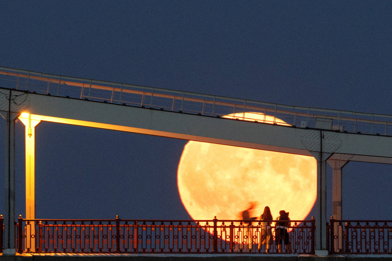 Residents watch as a full moon known as the 