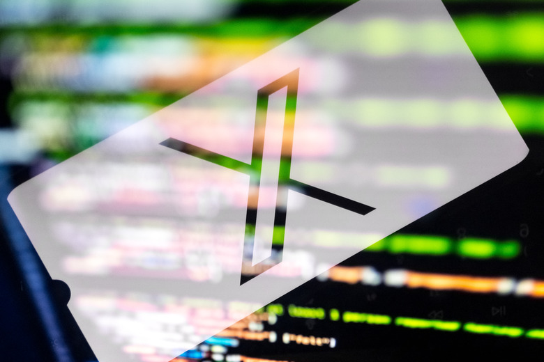 The X (former Twitter) logo appears on a smartphone screen, while algorithms appear on a laptop computer screen. (Photo by Nikolas Kokovlis/NurPhoto via Getty Images)