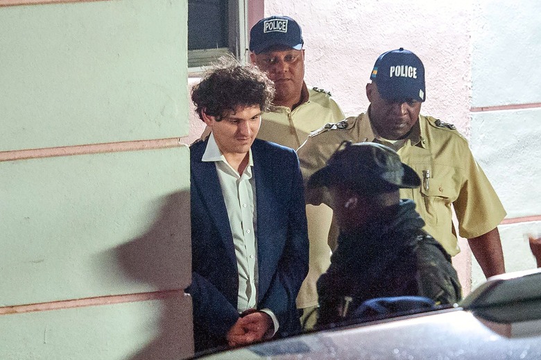 TOPSHOT - FTX founder Sam Bankman-Fried (L) is led away handcuffed by officers of the Royal Bahamas Police Force in Nassau, Bahamas on December 13, 2022. - Disgraced cryptocurrency tycoon Sam Bankman-Fried was hit with multiple criminal charges December 13, 2022, accused of committing one of the biggest financial frauds in US history. Bankman-Fried will serve time at The Bahamas Department of Corrections until February 8, 2023. (Photo by Mario Duncanson / AFP) (Photo by MARIO DUNCANSON/AFP via Getty Images)