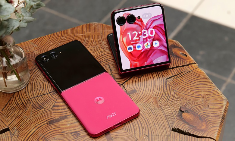 A pink leather Motorola Razr+ laying flat on a table next to a partially folded Razr+.