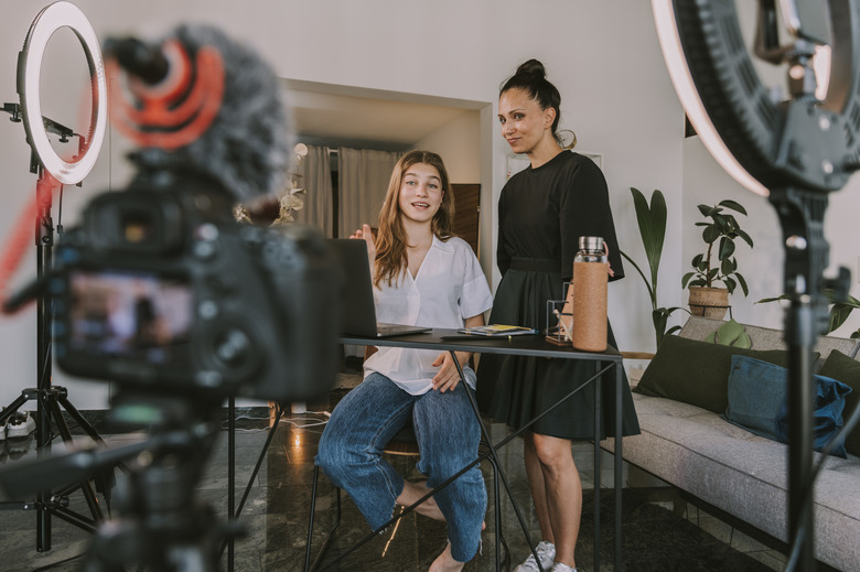 Female professionals working on laptop while vlogging at office