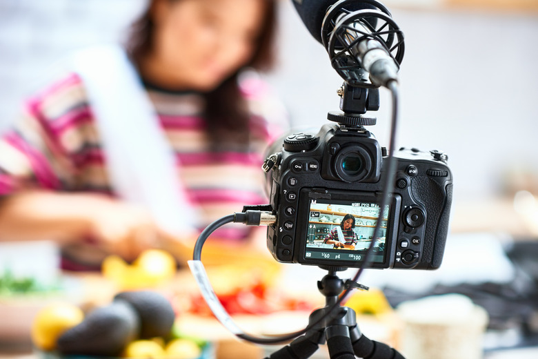 View through digital camcorder display of woman cooking meal, food vlogger making video at home, healthy eating, nutrition