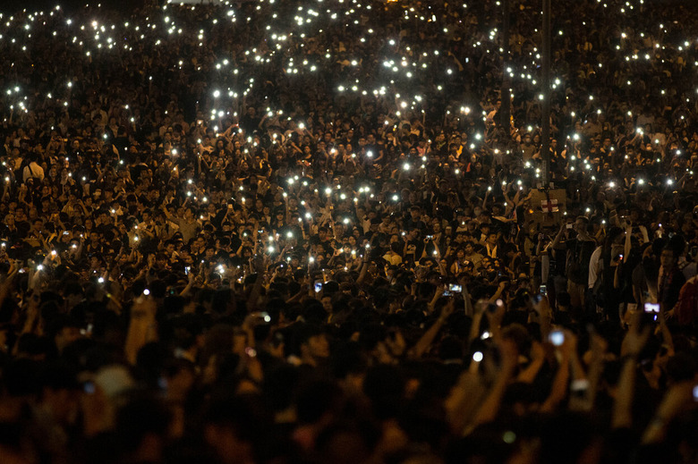 Nighttime shot of countless protestors holding up their phones’ flashlights.